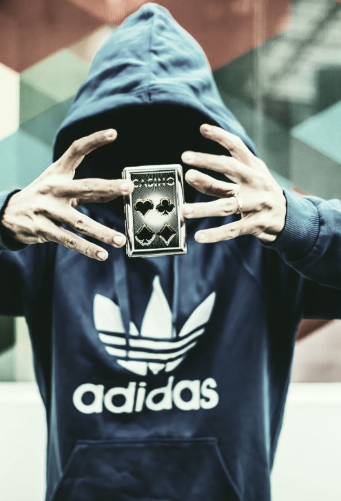 man with a deck of cards floating between his hands, which are in front of his concealed face